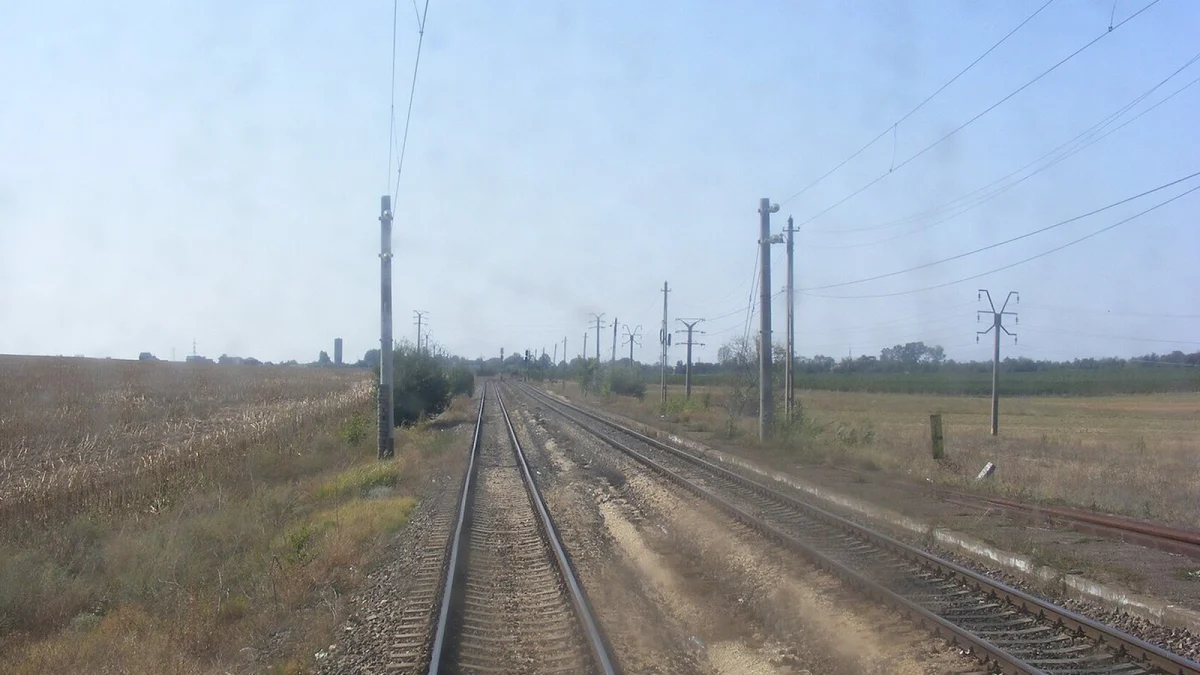 Linia de cale ferată Constanța–Mangalia lângă halta Agigea Ecluza, cu stâlpi de contact pe dreapta și cale simplă pe stânga (fotografie de arhivă, 2012)