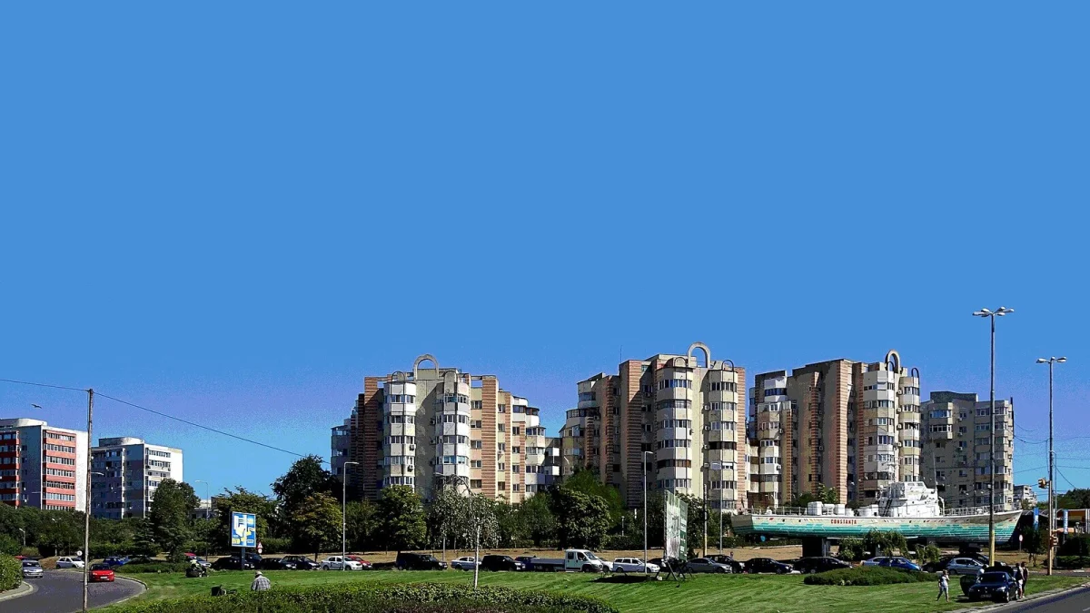 Blocuri de locuințe la intrarea în Constanța, cu o navă-monument inscripționată „Constanța” amplasată într-un sens giratoriu