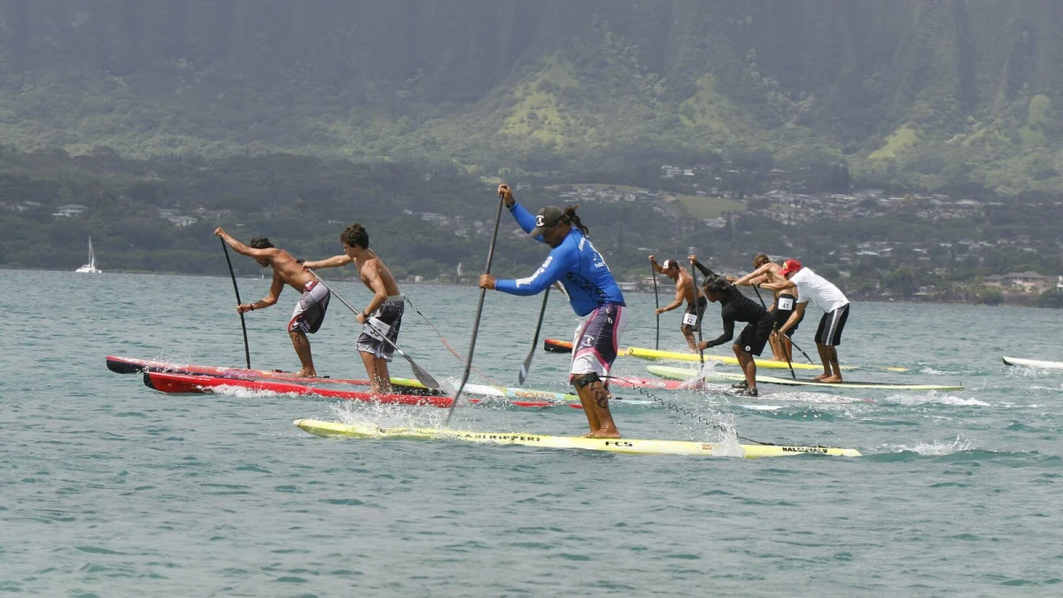 Sportivi pe plăci de stand up paddle, vâslind într-o cursă pe un golf, cu munți în fundal (imagine ilustrativă, nu este competiția din Italia)