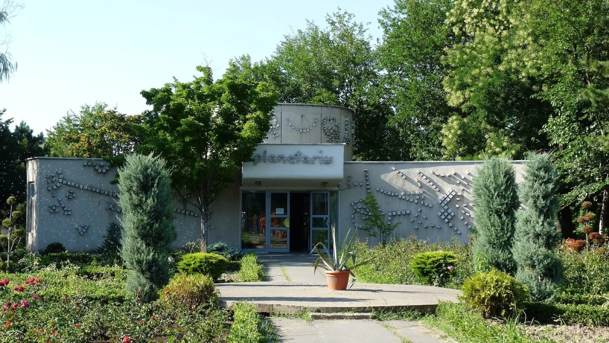 Clădirea Planetariului din Complexul Muzeal de Științe ale Naturii Constanța, cu fațadă gri decorată și alee printre arbuști și trandafiri (fotografie de arhivă, 2009)