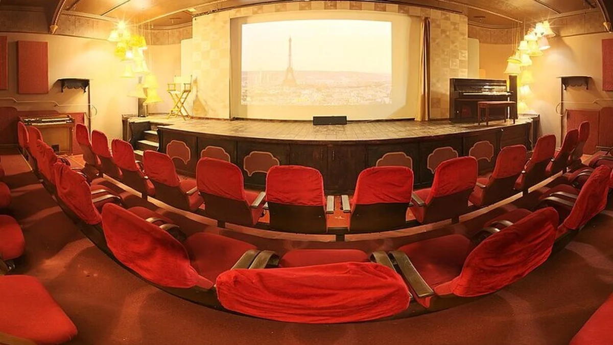 Sală de cinema cu fotolii roșii, ecran și scenă (imagine ilustrativă, nu este sala Centrului Jean Constantin)