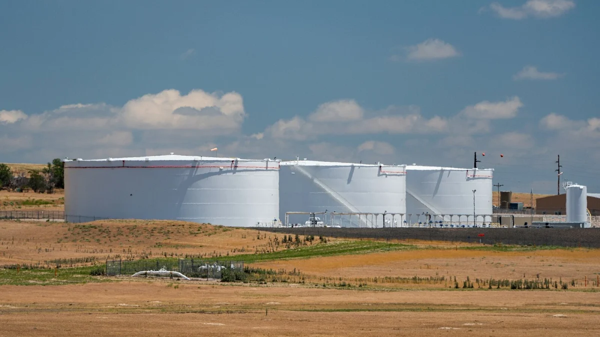 Trei rezervoare albe de țiței, pe un câmp, sub un cer cu nori (imagine ilustrativă, nu este Oil Terminal Constanța)