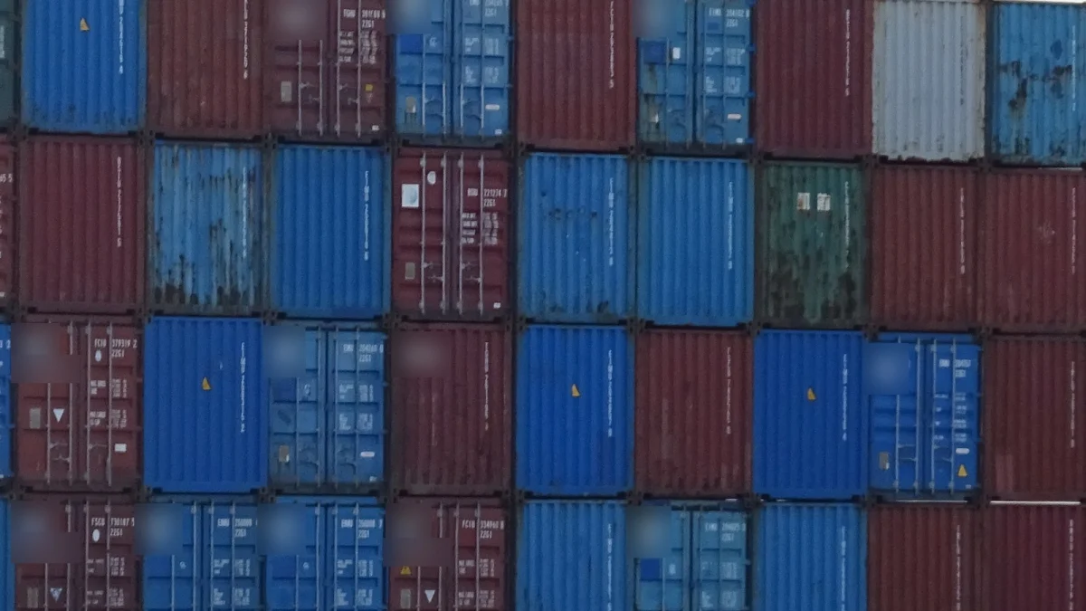 Containere maritime albastre și roșii, stivuite pe patru niveluri într-un terminal portuar, cu inscripțiile companiilor estompate (imagine ilustrativă, Portul Rotterdam, 2017)