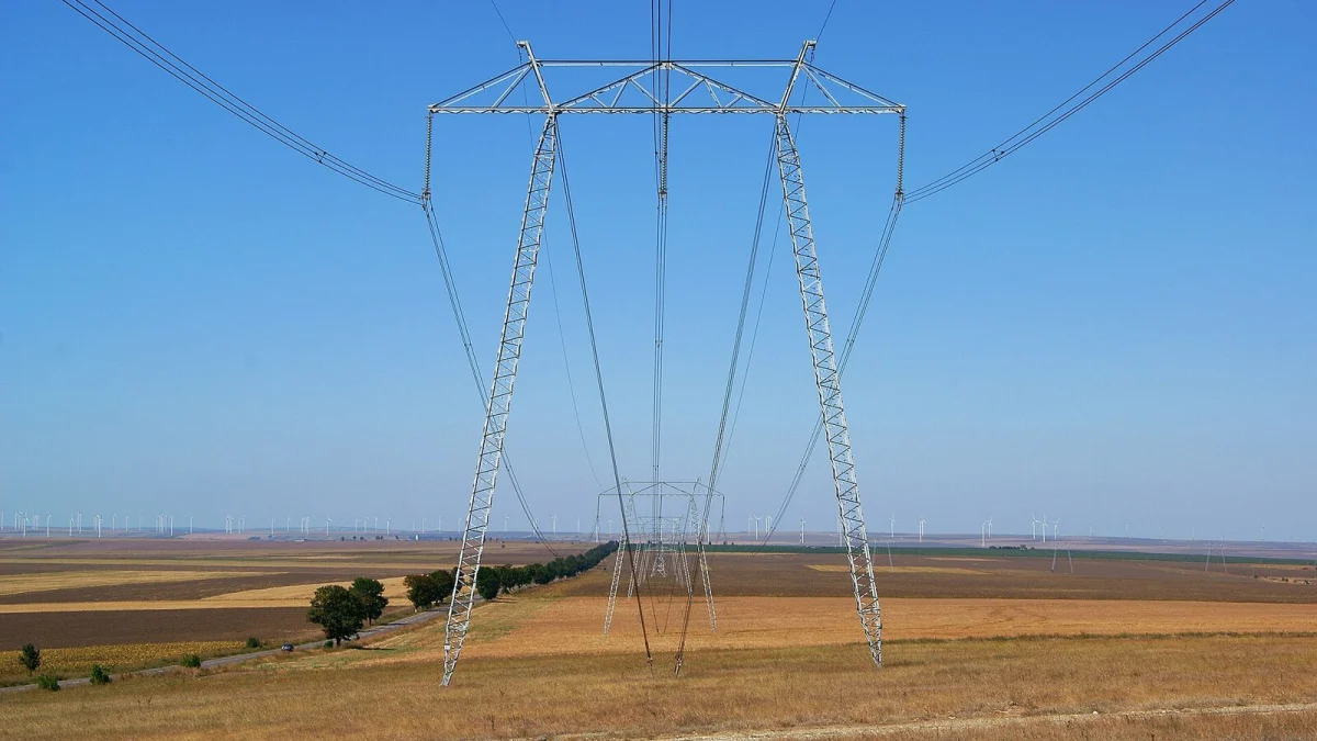 Linie electrică de înaltă tensiune de-a lungul DN 22, în județul Constanța, cu turbinele eoliene de la Fântânele–Cogealac în fundal (fotografie de arhivă)
