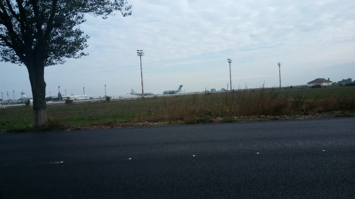 Vedere dinspre un drum din comuna Mihail Kogălniceanu spre aeroport, cu avioane parcate în depărtare