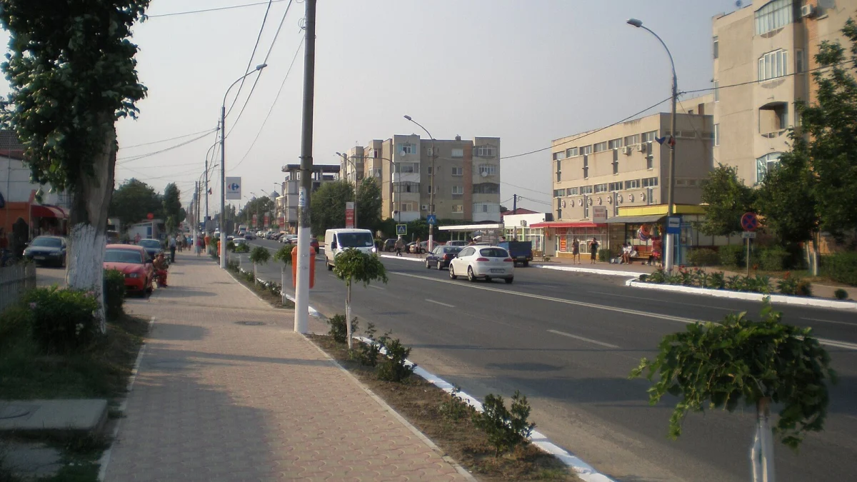 Stradă principală în orașul Ovidiu, cu trotuar, blocuri și magazine (fotografie de arhivă, 2008)