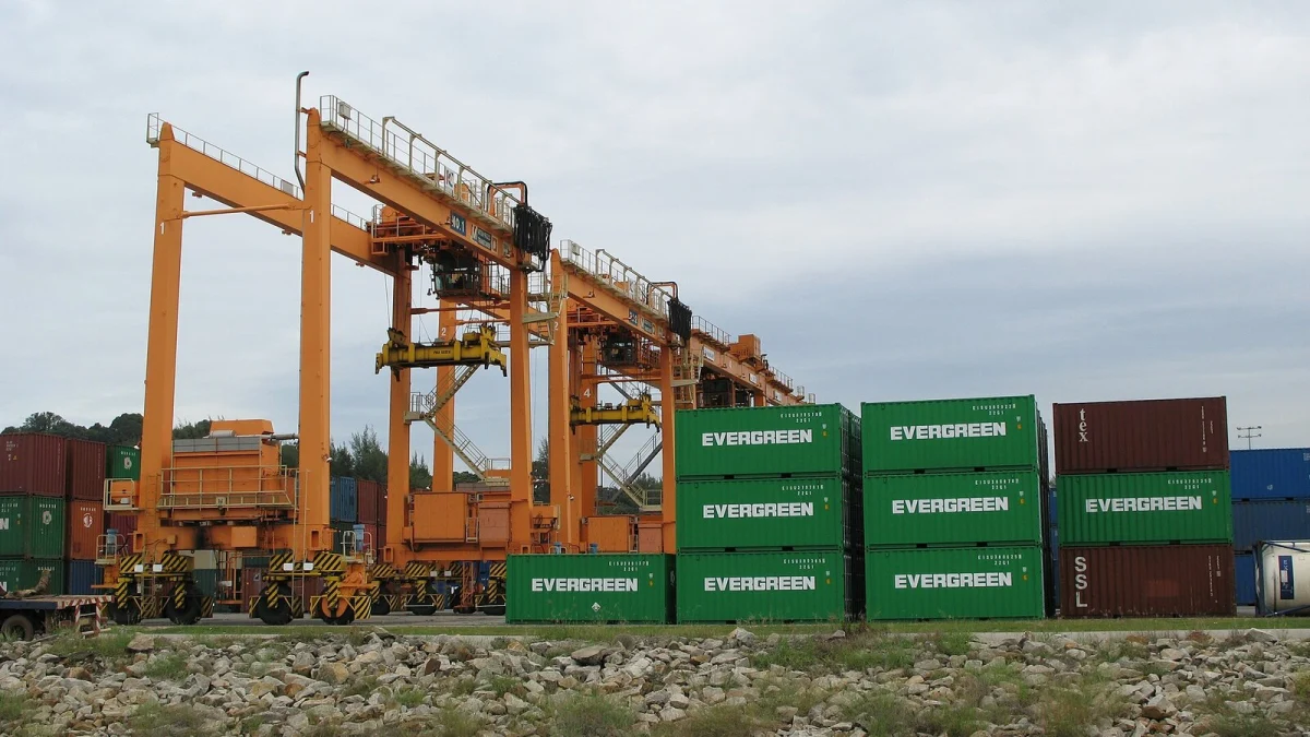 Macarale-portic pe pneuri și containere stivuite într-un terminal portuar (imagine ilustrativă, fotografie din alt port)