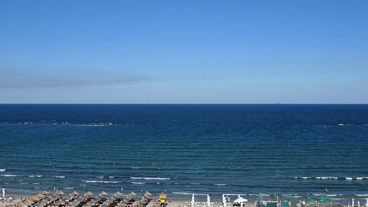 Marea Neagră văzută de sus, cu digurile de protecție și plaja din Mamaia cu umbrele de stuf (fotografie de arhivă, 2016)
