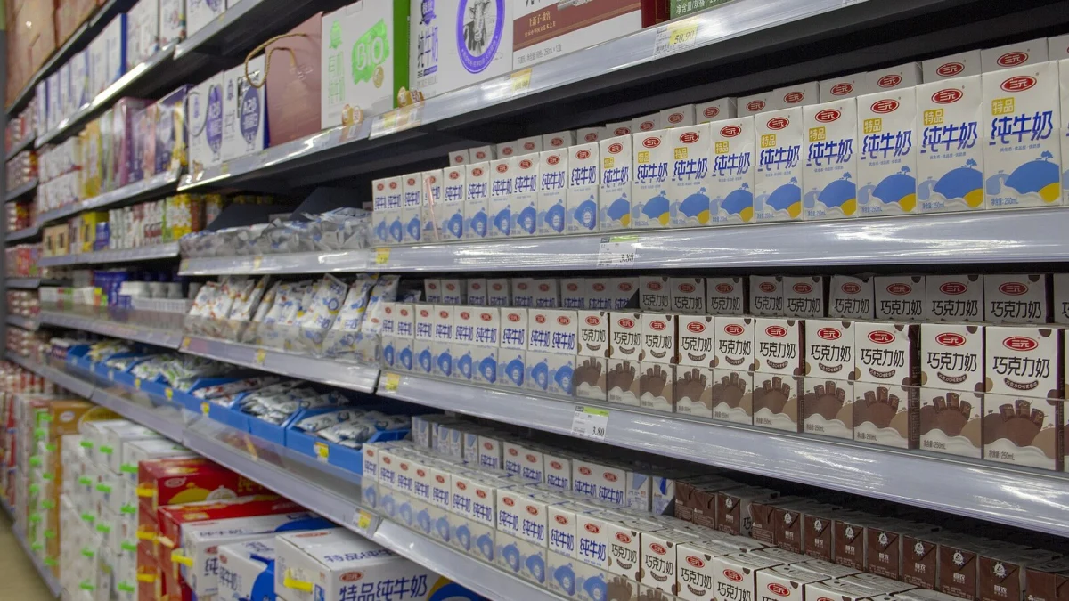 Rafturi de supermarket pline cu cutii de lapte și lapte cu cacao, cu etichete de preț pe margine (imagine ilustrativă, magazin din străinătate)