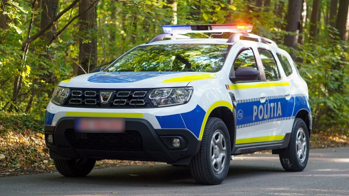 Autoturism Dacia Duster al Poliției Române, alb cu albastru și dungi galbene, cu girofarul aprins, într-o pădure (imagine ilustrativă, 2020, nu este din Constanța), cu numărul de înmatriculare estompat