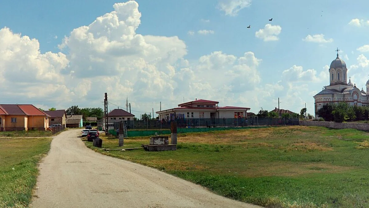 Centrul satului Osmancea, comuna Mereni, cu o biserică și case, sub un cer cu nori (imagine ilustrativă, localitatea nu este una dintre cele zece comune)