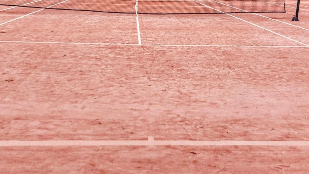 Teren de tenis pe zgură, cu linii albe și plasa în fundal (imagine ilustrativă, nu este de la Constanța)
