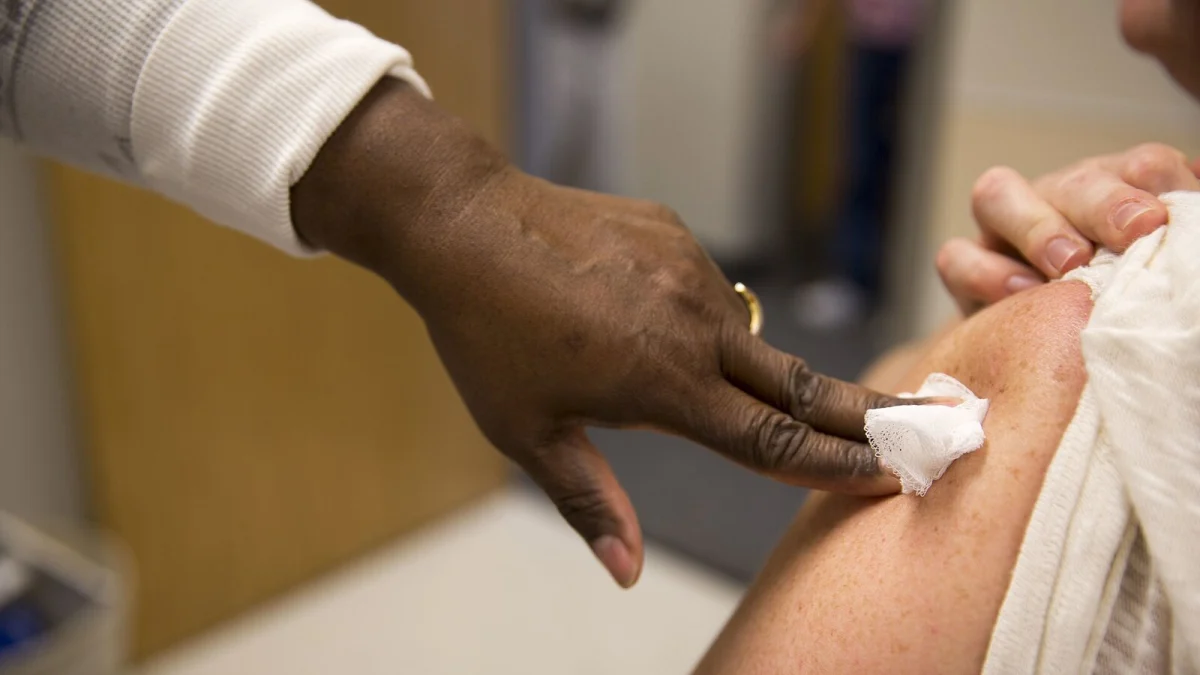Mâna unui cadru medical apasă un tampon de vată pe brațul unui pacient, după administrarea vaccinului antigripal (imagine ilustrativă)