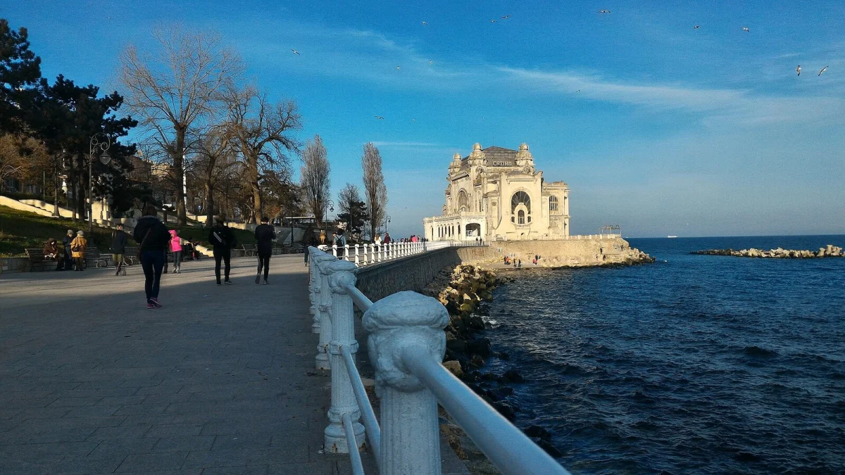 Faleza din Constanța, cu Cazinoul în fundal; clădirea Acvariului se află vizavi de Cazino (fotografie de arhivă, 2018)