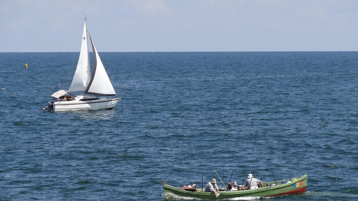 O barcă cu pânze și o barcă de pescari pe mare, la Constanța